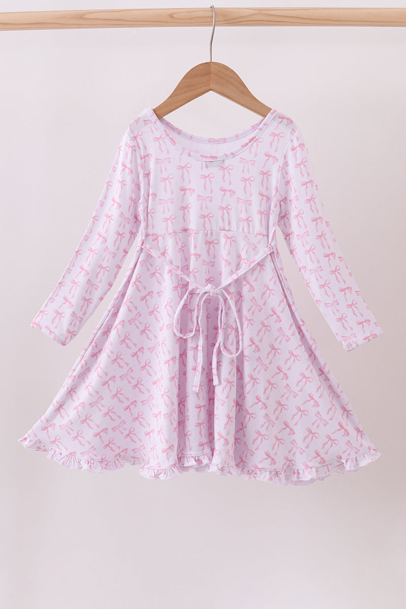 Young girl wearing a pink dress with a subtle pattern on a white background